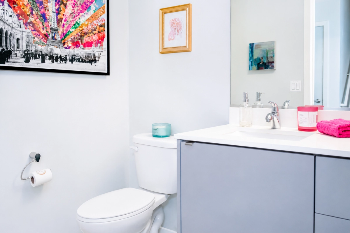 Bright clean Seattle bathroom with a toilet, sink and bright framed picture.